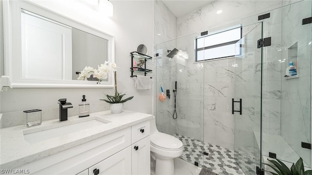 bathroom featuring vanity, toilet, and a shower with door