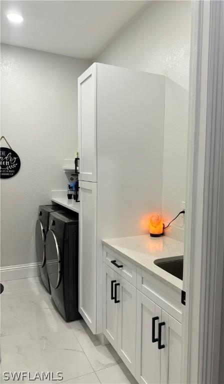 laundry room featuring cabinets, independent washer and dryer, and sink