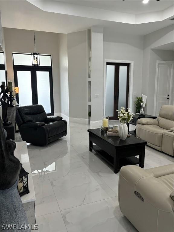 living room with a chandelier, a towering ceiling, and french doors