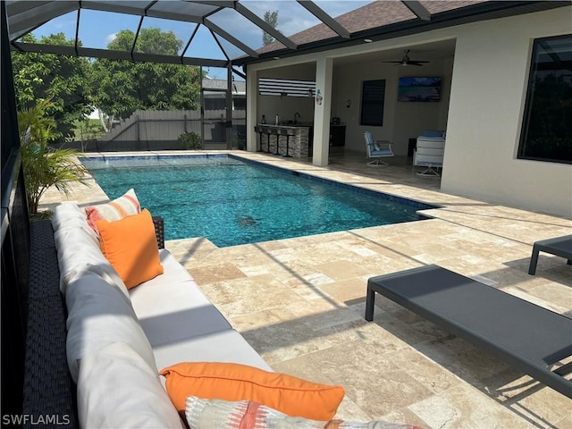 view of pool with outdoor lounge area, ceiling fan, a patio, and glass enclosure