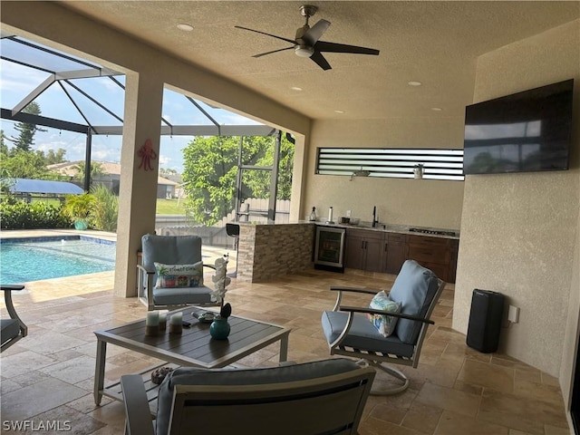 view of patio / terrace with a lanai, ceiling fan, sink, exterior kitchen, and wine cooler