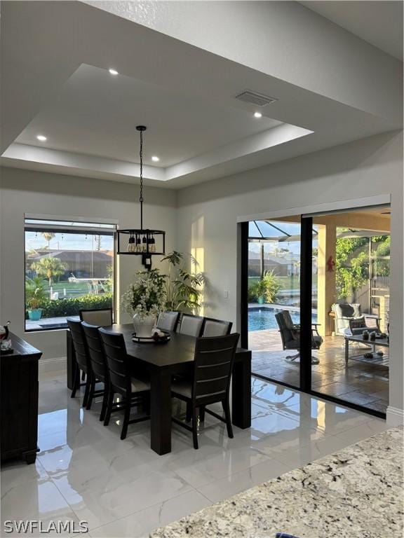 dining room featuring a healthy amount of sunlight, an inviting chandelier, and a tray ceiling