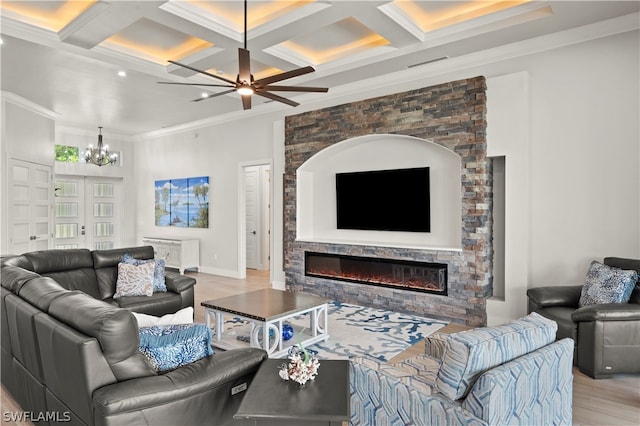 living room featuring coffered ceiling, light wood-type flooring, a fireplace, ornamental molding, and beamed ceiling