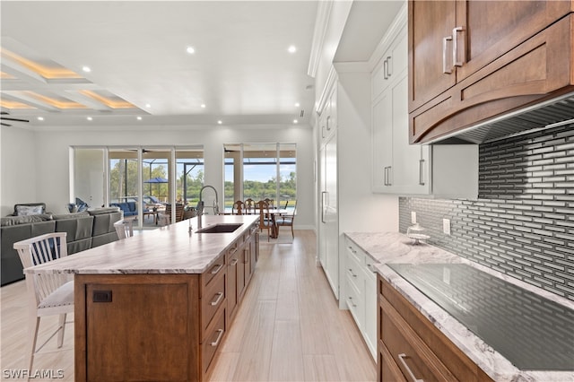 kitchen with ceiling fan, sink, white cabinetry, and a large island