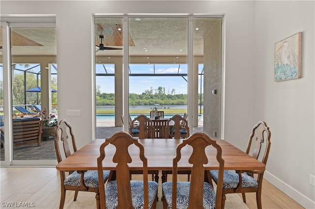 dining room with a water view, ceiling fan, and light hardwood / wood-style flooring