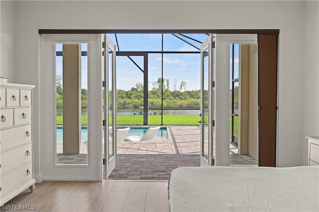 bedroom with light wood-type flooring and a water view