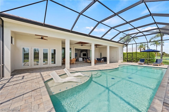 view of swimming pool featuring glass enclosure, a patio area, french doors, outdoor lounge area, and ceiling fan