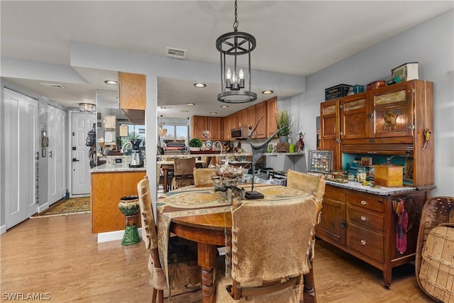 dining space with light hardwood / wood-style floors and a notable chandelier