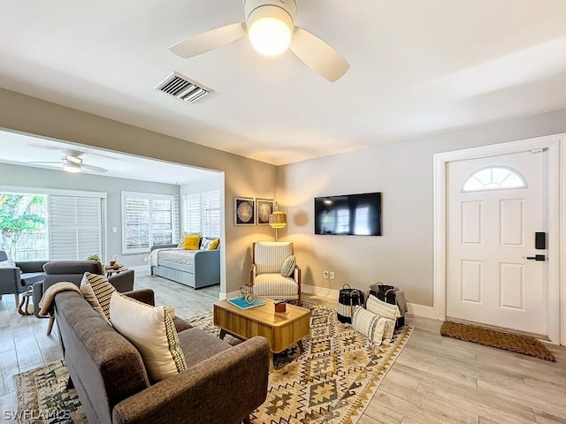 living room featuring ceiling fan, light wood-style flooring, and baseboards