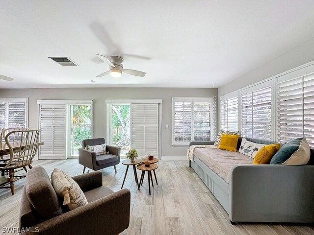 living area featuring a ceiling fan, baseboards, and light wood-style floors
