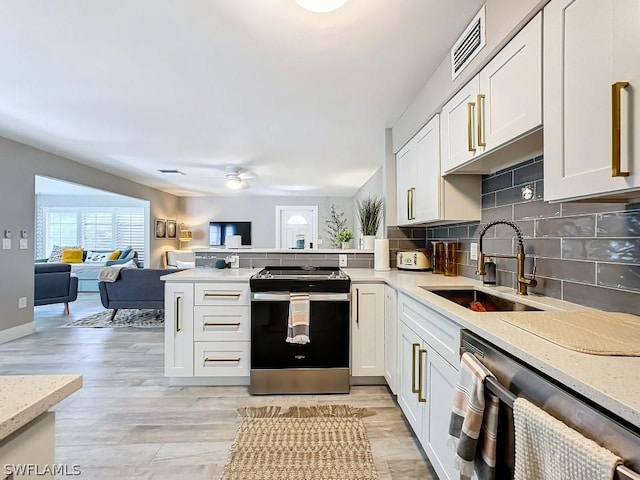 kitchen featuring stainless steel appliances, a sink, a peninsula, a ceiling fan, and open floor plan