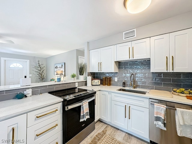 kitchen with white cabinetry, light wood-type flooring, appliances with stainless steel finishes, backsplash, and sink