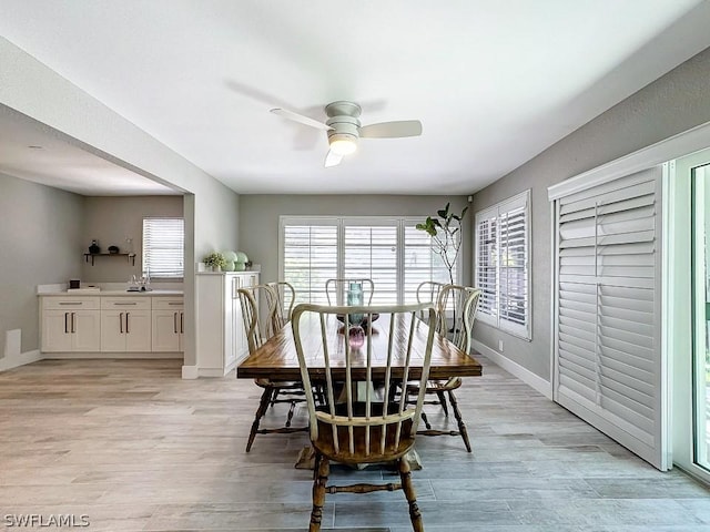 dining space featuring a ceiling fan, baseboards, and light wood finished floors