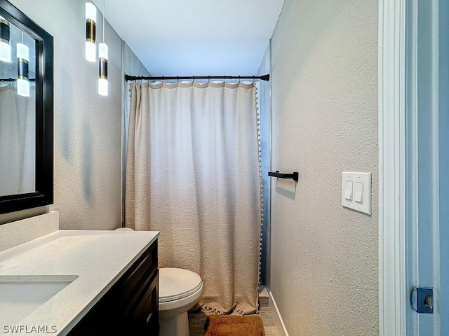 full bathroom with a textured wall, vanity, toilet, curtained shower, and baseboards