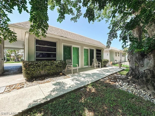 back of property with roof with shingles, stucco siding, fence, and a patio area