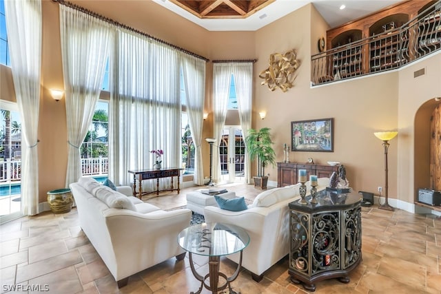 living room with coffered ceiling, a towering ceiling, and beamed ceiling