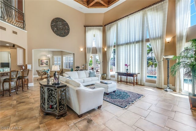 living room with a high ceiling, an inviting chandelier, and coffered ceiling