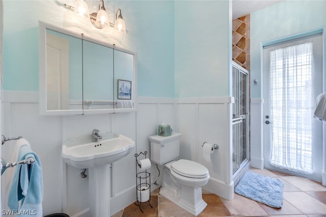 bathroom with toilet, a shower with door, and tile patterned floors