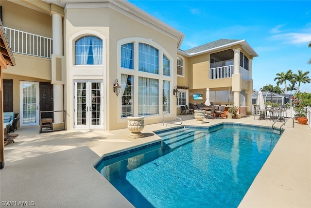 view of swimming pool with a lanai, a patio, and french doors