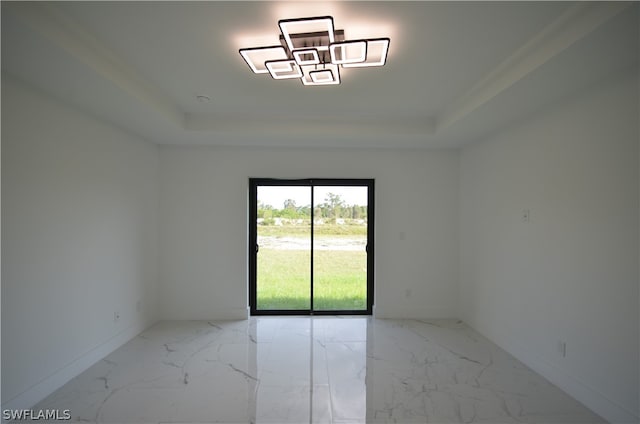 spare room with tile floors and a raised ceiling