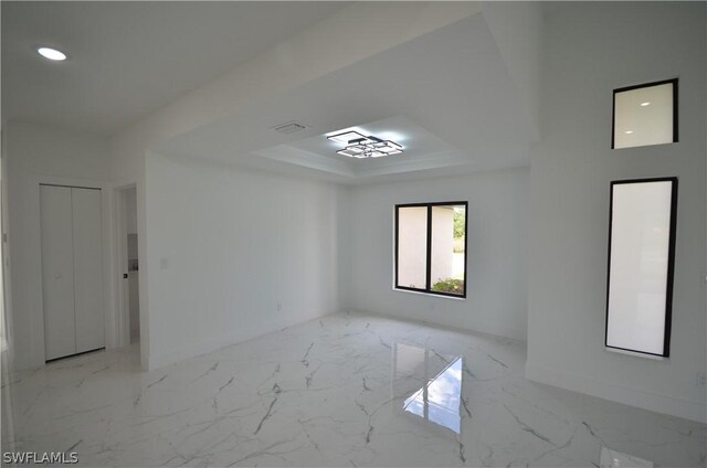 tiled spare room with a tray ceiling