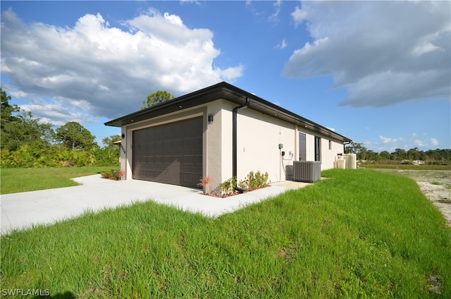 view of side of property with a garage, a yard, and central AC unit