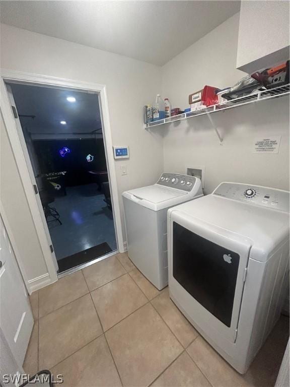 laundry room with independent washer and dryer and light tile patterned floors