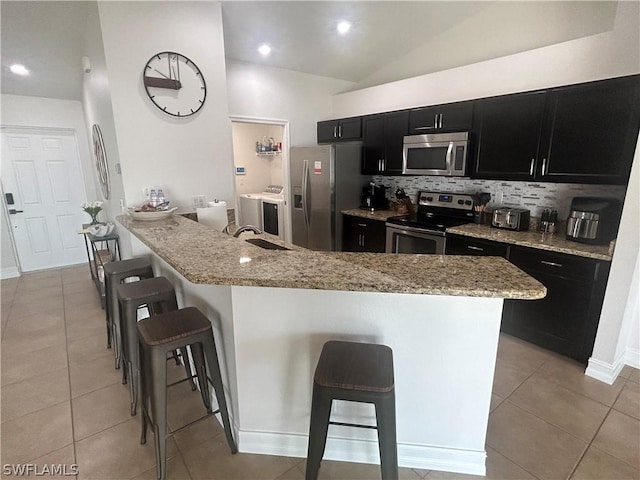 kitchen featuring a breakfast bar area, light stone counters, lofted ceiling, and appliances with stainless steel finishes