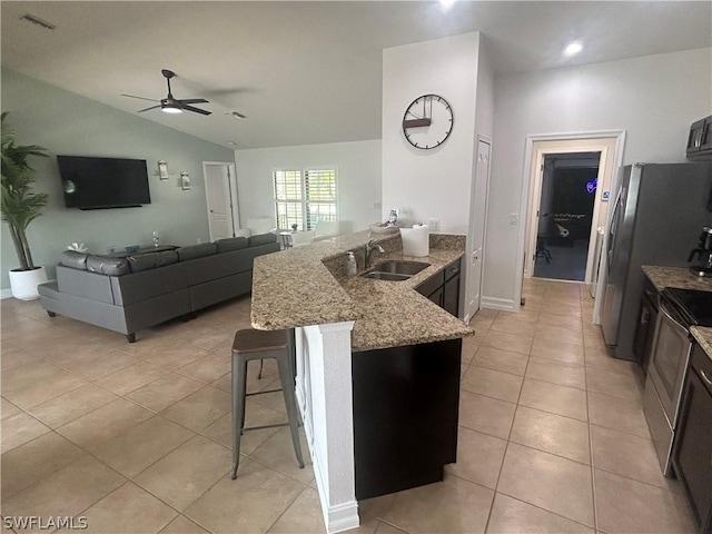 kitchen with ceiling fan, sink, vaulted ceiling, a kitchen bar, and light tile patterned flooring