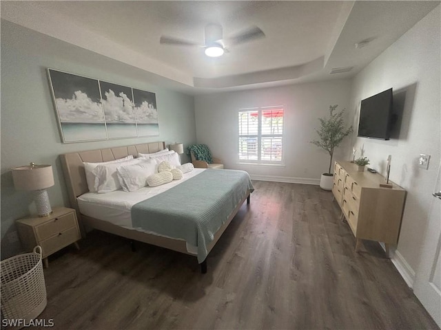 bedroom with dark hardwood / wood-style flooring, a raised ceiling, and ceiling fan