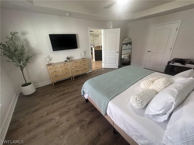 bedroom featuring dark hardwood / wood-style floors, ceiling fan, and a tray ceiling