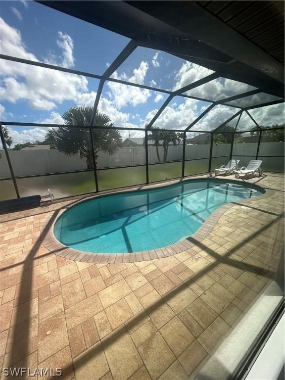 view of pool featuring glass enclosure and a patio