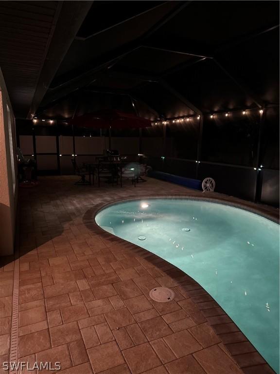 pool at night with a patio area and a lanai