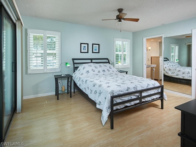 bedroom with ceiling fan, light hardwood / wood-style floors, a textured ceiling, and multiple windows