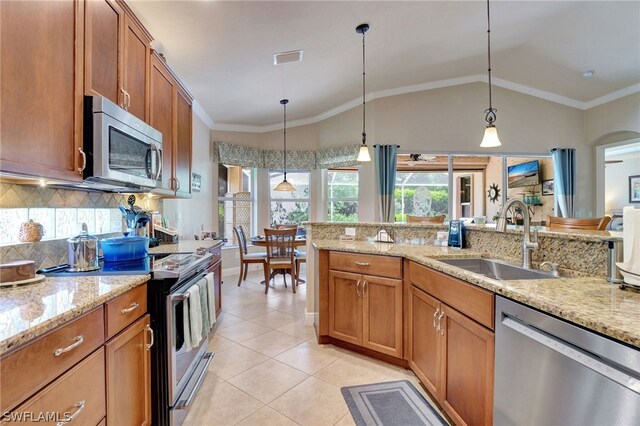 kitchen with sink, light stone countertops, vaulted ceiling, decorative light fixtures, and appliances with stainless steel finishes