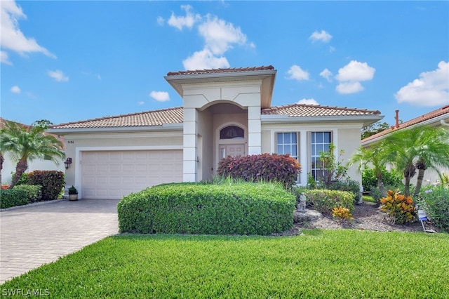 mediterranean / spanish house featuring a front yard and a garage