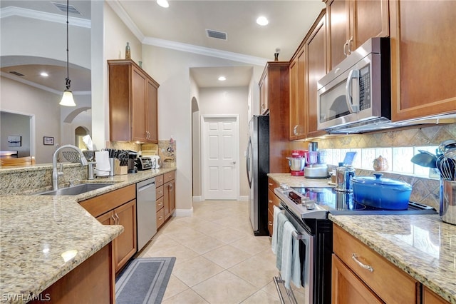 kitchen with light tile patterned flooring, sink, light stone counters, decorative light fixtures, and appliances with stainless steel finishes