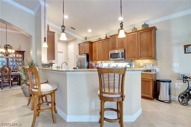 kitchen featuring appliances with stainless steel finishes, light stone countertops, hanging light fixtures, and a breakfast bar area