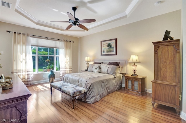 bedroom with ornamental molding, a raised ceiling, ceiling fan, and light wood-type flooring