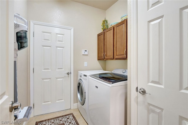 washroom with independent washer and dryer, cabinets, and light tile patterned floors