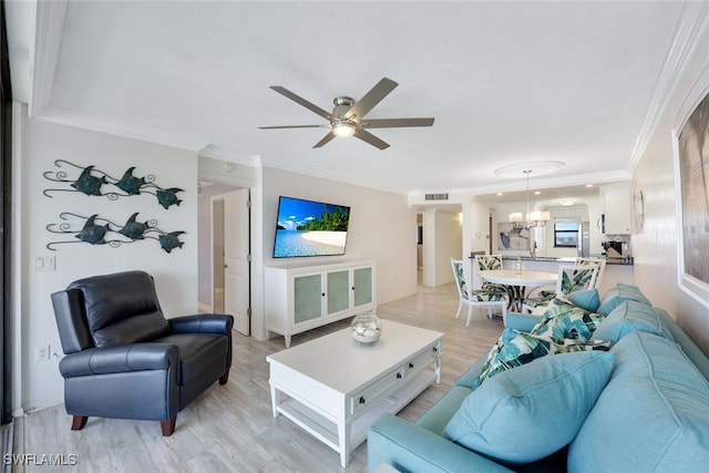 living room with ornamental molding, ceiling fan with notable chandelier, and light hardwood / wood-style floors