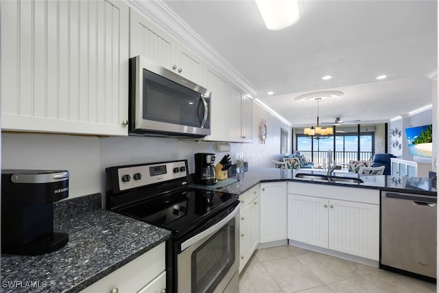 kitchen featuring a notable chandelier, ornamental molding, white cabinetry, stainless steel appliances, and sink