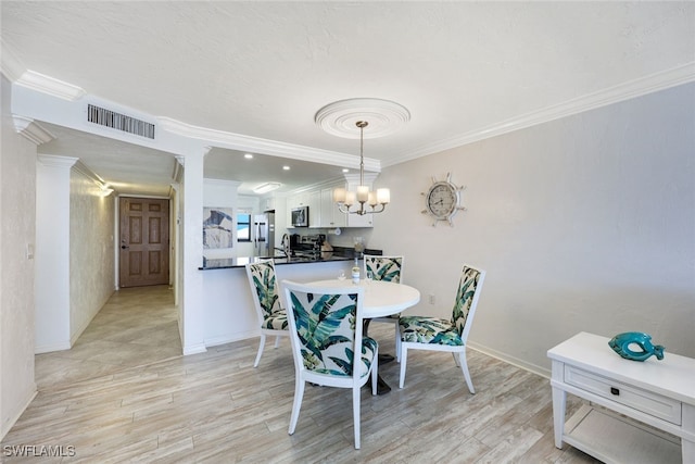 dining room with light hardwood / wood-style floors, an inviting chandelier, crown molding, and sink