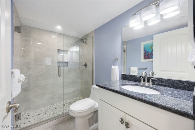 bathroom featuring toilet, a shower with door, and vanity