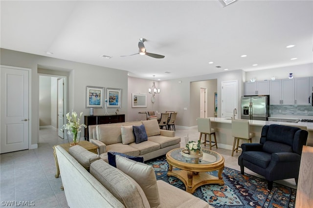 tiled living room featuring sink and ceiling fan with notable chandelier