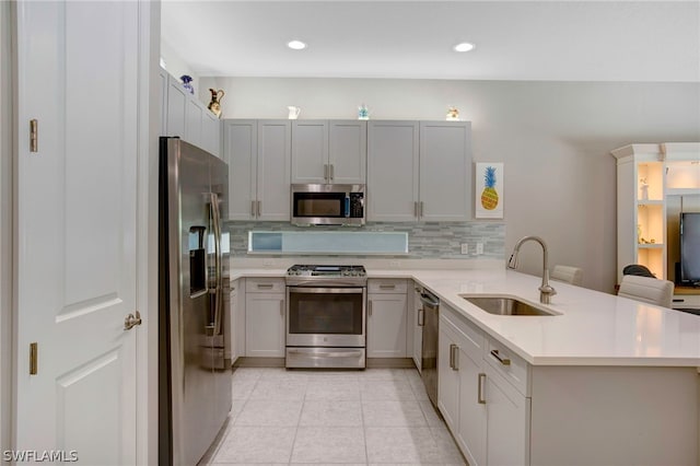 kitchen with light tile patterned flooring, kitchen peninsula, sink, and appliances with stainless steel finishes