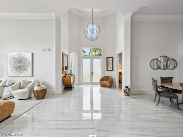 entrance foyer featuring french doors, a towering ceiling, crown molding, and an inviting chandelier