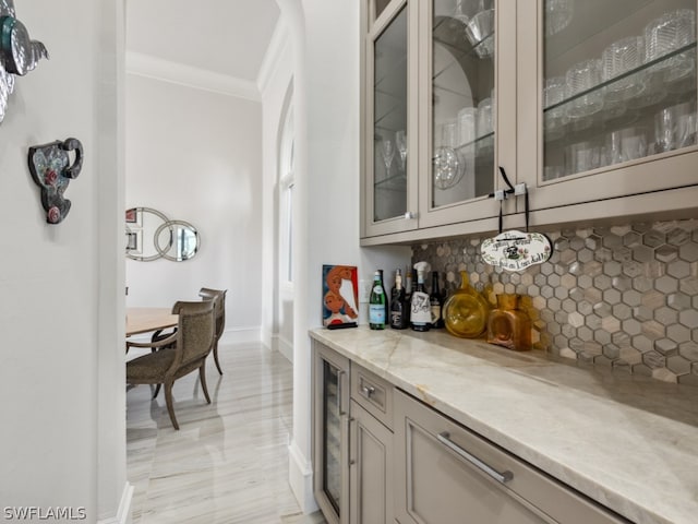 bar with backsplash, light stone counters, beverage cooler, and crown molding