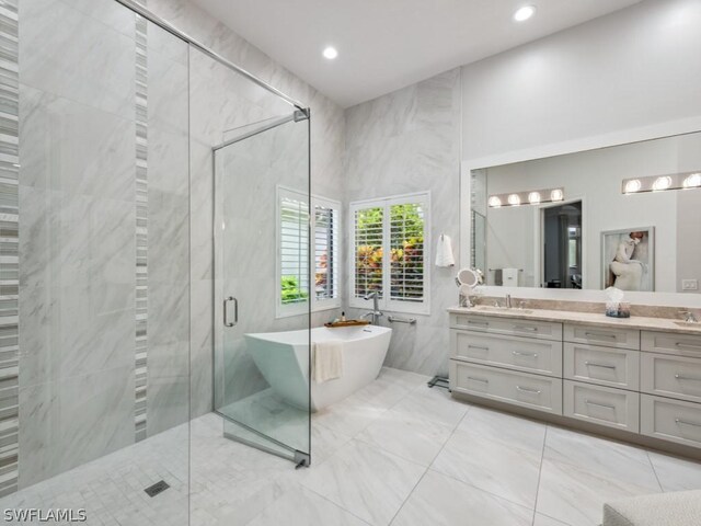 bathroom featuring separate shower and tub, vanity, and tile walls