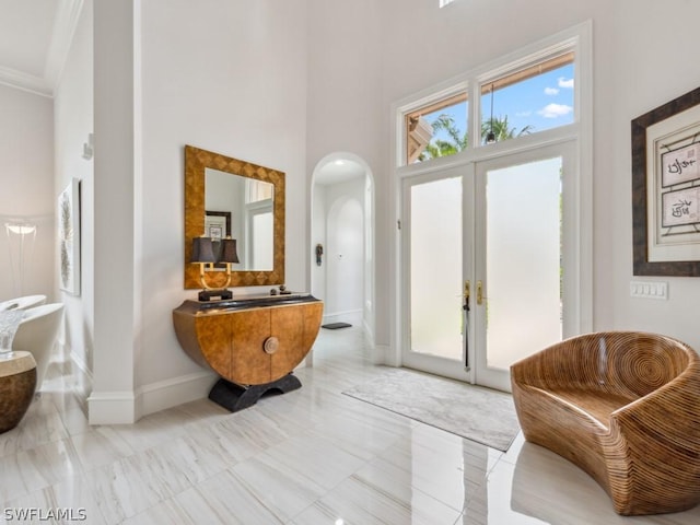 entryway featuring a high ceiling, ornamental molding, and french doors